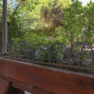 A small garden area with lush greenery and a decorative metal fence on a wooden structure.