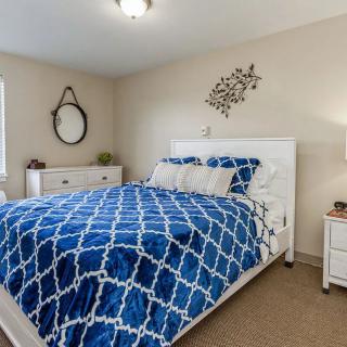 A cozy bedroom with blue patterned bedding, a white bed frame, and matching furniture.