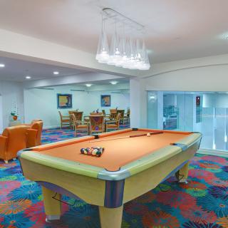 A modern game room featuring a billiards table with colorful carpeting and comfortable seating.