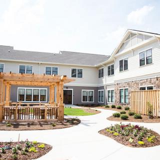 A spacious residential courtyard with well-maintained gardens and a wooden pergola.