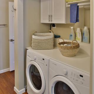 A neatly organized laundry room with a washing machine, dryer, and storage shelves.