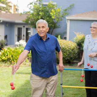 Seniors enjoying a game of ladder toss in the backyard.