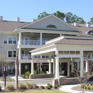 A large, multi-story residential building with a covered entrance and balconies.