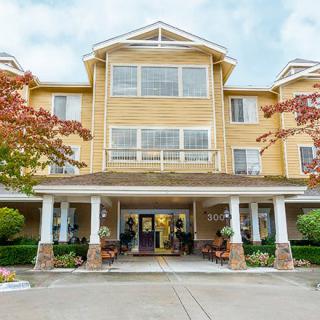 A multi-story residential building with a welcoming entrance surrounded by trees.