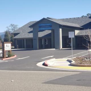 A building with a parking lot in front, featuring signage and clear skies.