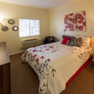A cozy bedroom with floral bedding and decorative wall art.