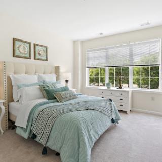 A serene and modern bedroom featuring soft color tones and natural light.