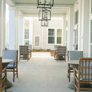 A serene outdoor patio area featuring tables and chairs under soft natural light.