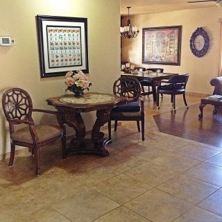 A cozy interior space with a small table and chairs, decorated with wall art and flowers.
