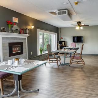 A modern dining area with a fireplace, featuring tables and chairs on a wooden floor.