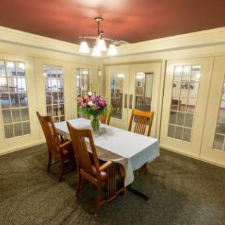 A cozy dining area with a table set for meals, surrounded by elegant chairs and decorated with fresh flowers.