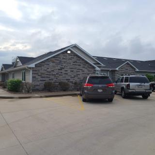 An exterior view of a building with parked cars in a cloudy setting.