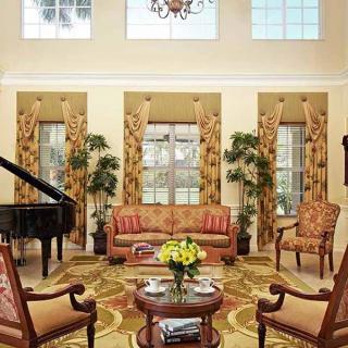 A spacious living room with elegant traditional decor, featuring a grand piano and ample natural light.