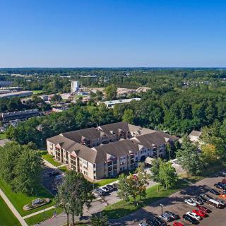 Aerial view of a suburban apartment complex surrounded by trees and parking lots.