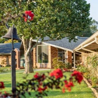 A charming house surrounded by a well-maintained garden with flowering plants and trees.