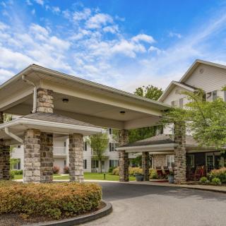 A view of a building entrance with stone pillars and a driveway.