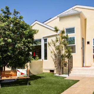 A modern house with a well-maintained front yard, featuring a tree and a bench on a sunny day.