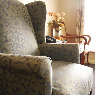 A cozy upholstered armchair in a warmly lit living room corner.