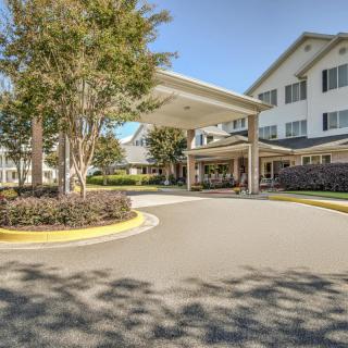 A welcoming entrance to a large building with well-maintained landscaping and a clear blue sky.