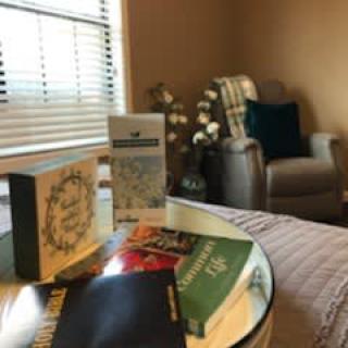 A cozy reading nook with a collection of books on a table near a comfortable chair.
