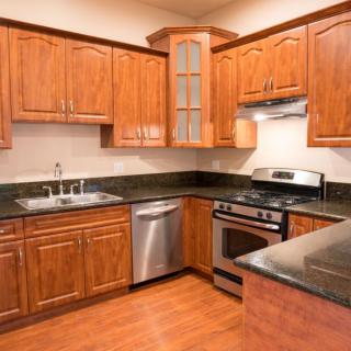 A modern kitchen with wooden cabinets, stainless steel appliances, and a dark countertop.