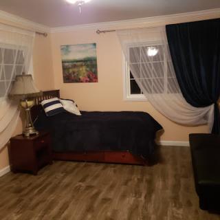 A cozy and well-decorated bedroom featuring a bed, lamp, and elegant curtains.