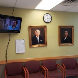 A waiting room featuring portraits on the wall, a television, and seating for visitors.