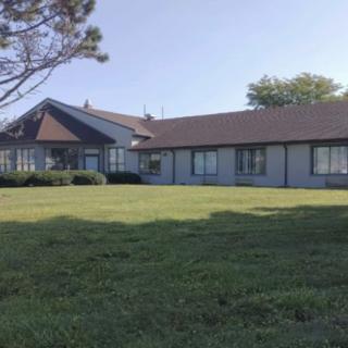 A residential building with a well-maintained lawn and surrounding trees under a clear sky.