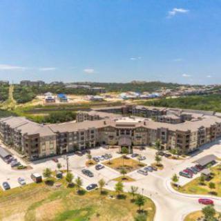 Aerial view of a large apartment complex surrounded by parking lots and open landscape.