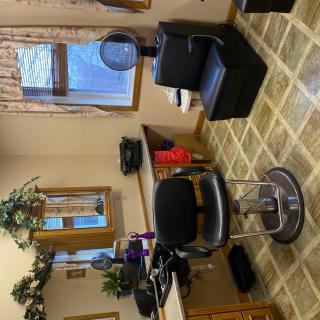 A cozy salon interior with a styling chair and hairdressing equipment.