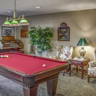 A cozy recreation room featuring a red pool table and comfortable seating.