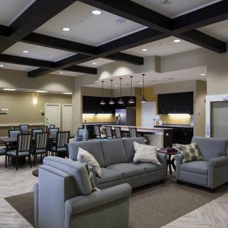 A modern open-plan living area with stylish furniture, including sofas and a dining table, seamlessly integrated with a kitchen.