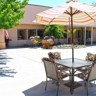 A sunny outdoor patio with a table, chairs, and a striped umbrella.