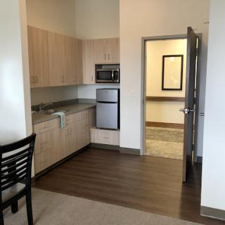 A modern kitchen in an apartment featuring wooden flooring and stainless steel appliances.
