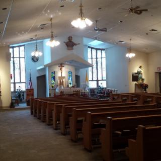 Interior view of a church with wooden pews and stained glass windows.