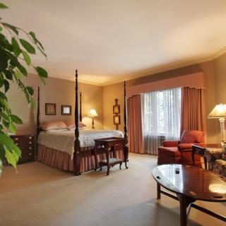 A cozy and well-decorated bedroom featuring a four-poster bed, elegant curtains, and warm lighting.