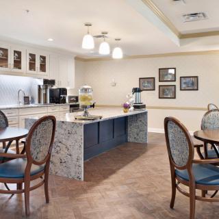 A cozy dining area with a modern kitchen setup, featuring round tables and elegant chairs.