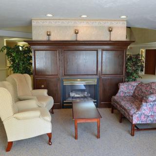 A cozy living room setup featuring a fireplace, armchair, and sofa.