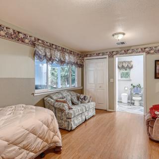 A cozy bedroom with a bed, couch, and wooden flooring.