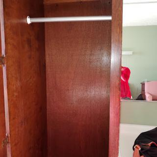 An empty wooden closet with a hanging rod, showcasing minimalist storage.