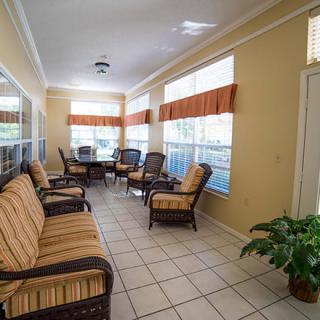 A cozy sunroom featuring comfortable seating and large windows allowing natural light to fill the space.