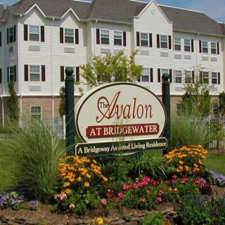 Front view of Avalon at Bridgewater apartments with a landscaped sign and flowers.