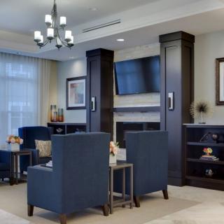 A modern living room with blue chairs, a television, and elegant lighting.