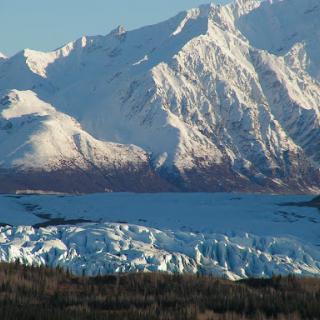 A breathtaking view of a glacier surrounded by majestic snow-capped mountains.