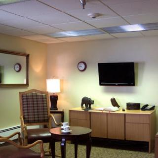 A cozy office waiting room featuring comfortable furniture, a television, and decorative elements.