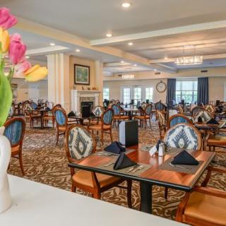A spacious and elegantly decorated dining area with neatly arranged tables and chairs, featuring floral decorations.