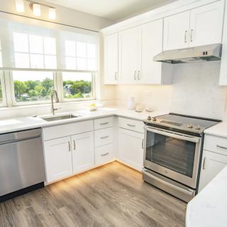 A bright, modern kitchen with white cabinets and stainless steel appliances.