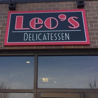 Leo's Delicatessen storefront with signage on a brick building.
