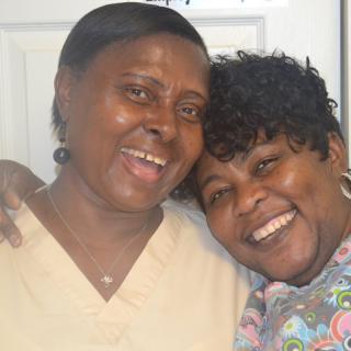 Two friends smiling and hugging indoors.