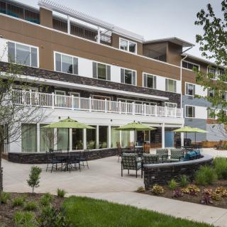 A modern apartment complex with a landscaped patio area and outdoor seating.